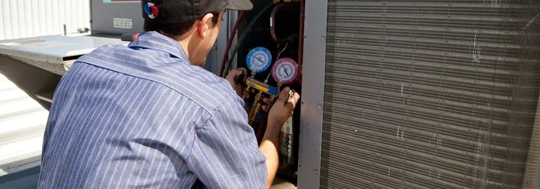 HVAC technician servicing a condenser unit in Muncie