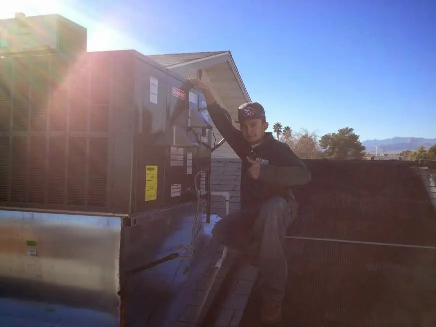 HVAC technician performing Heat Pump Repair on a rooftop unit in Muncie